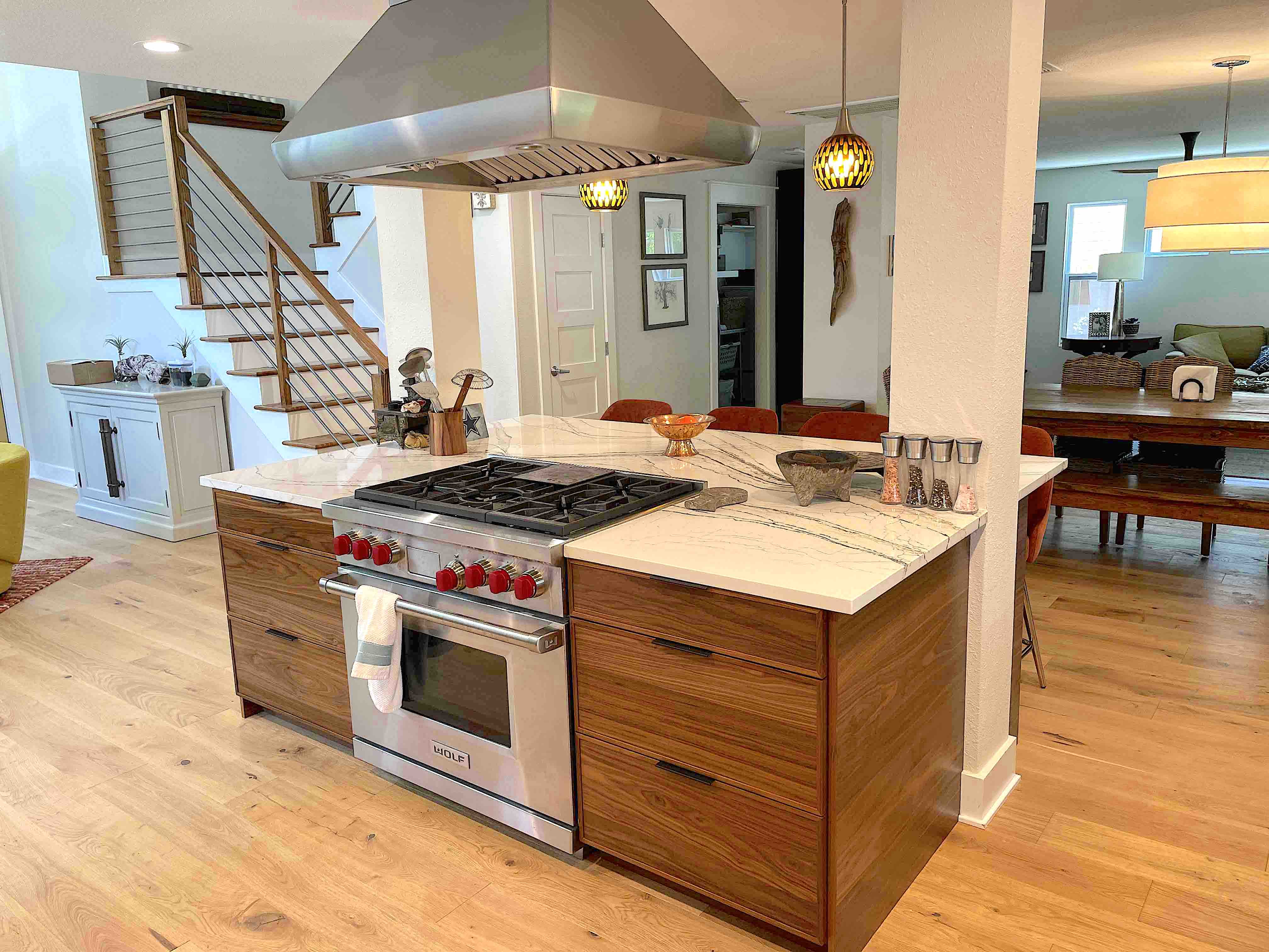 Modern kitchen island with Wolf range, marble countertop, wood cabinets, and stainless steel range hood.