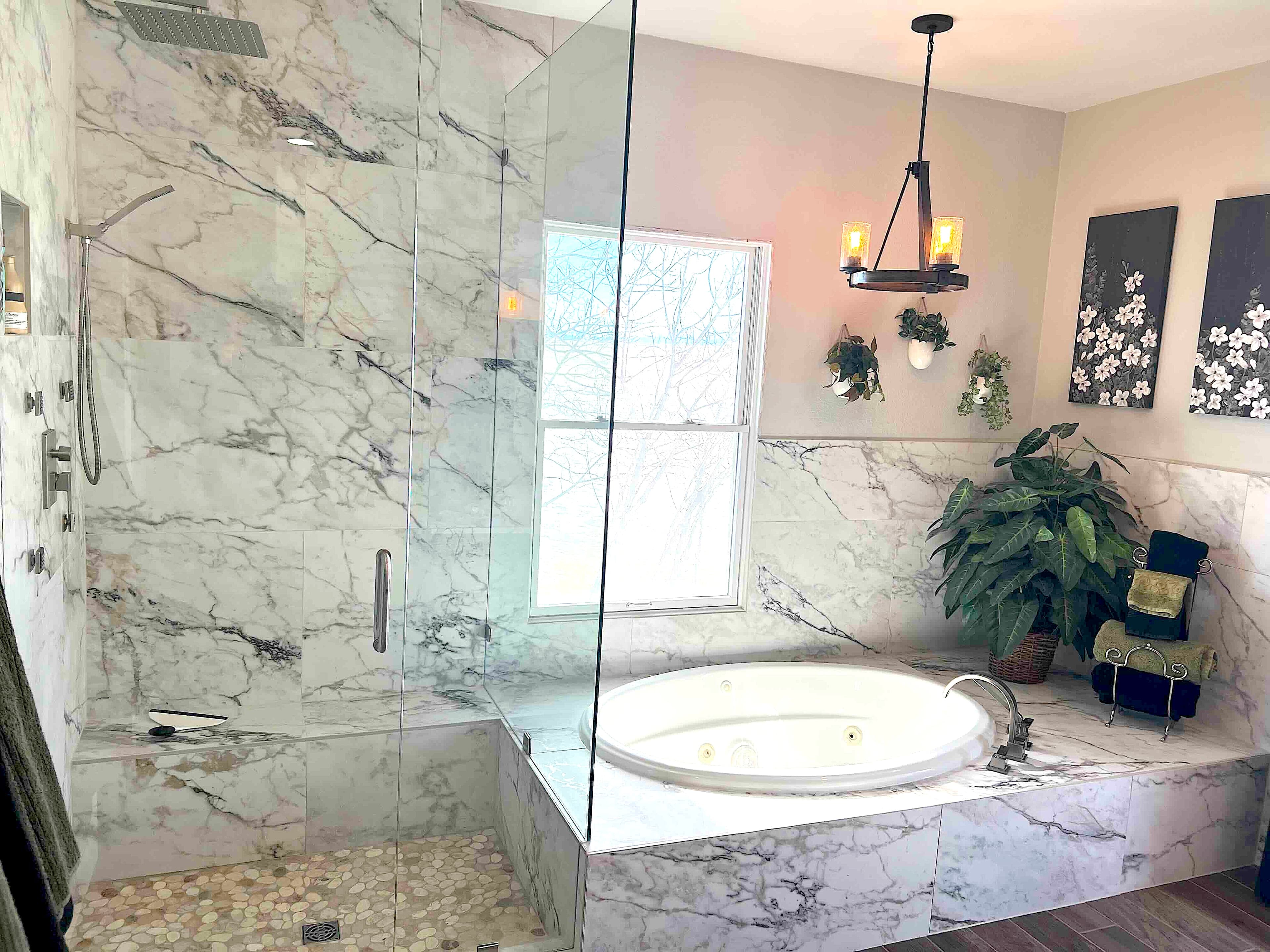 Modern marble bathroom featuring a glass walk-in shower and a large circular soaking tub.